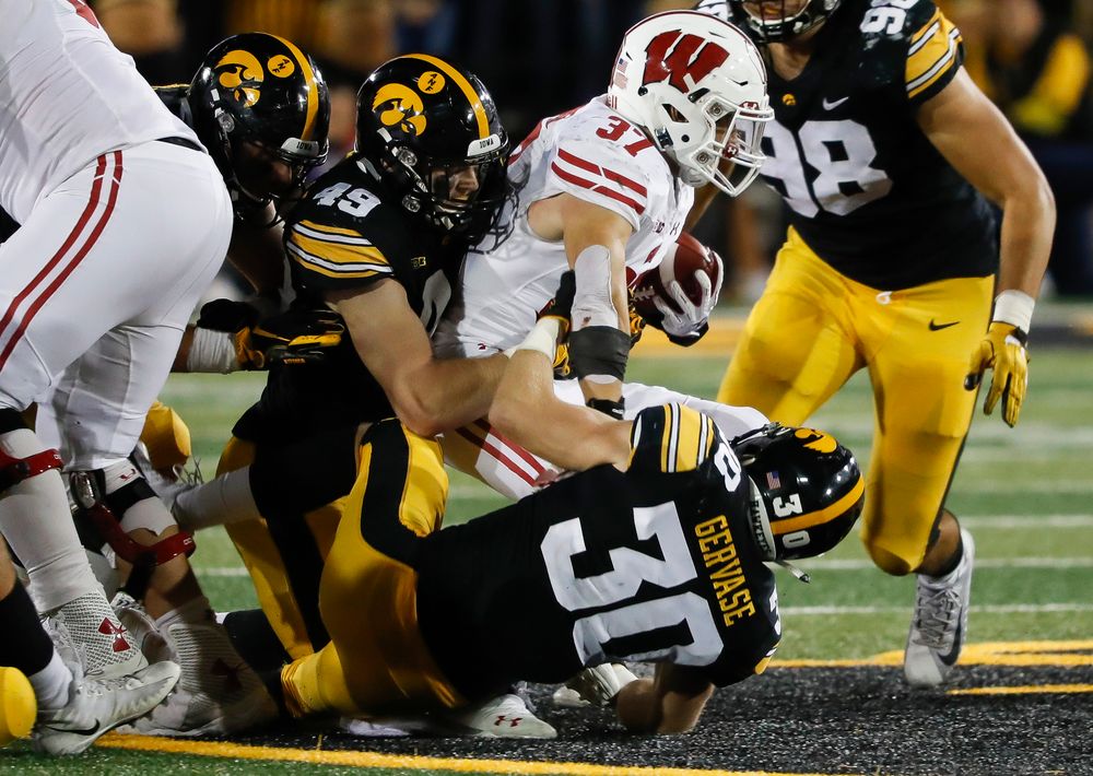 Iowa Hawkeyes linebacker Nick Niemann (49) and Iowa Hawkeyes defensive back Jake Gervase (30) make a tackle during a game against Wisconsin at Kinnick Stadium on September 22, 2018. (Tork Mason/hawkeyesports.com)