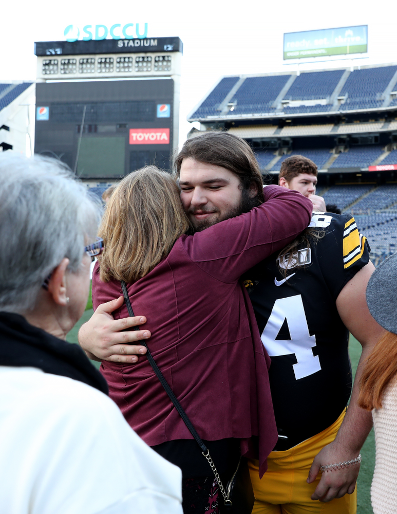 Iowa Hawkeyes offensive lineman Kyler Schott (64) hugs family members following the team photo Wednesday, December 25, 2019 at SDCCU Stadium in San Diego. (Brian Ray/hawkeyesports.com)