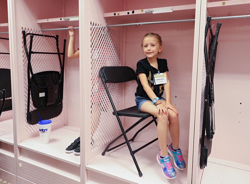 Kid Captain Charlotte Keller sits in a locker in the visitor’s pink locker room during Kids Day at Kinnick Stadium in Iowa City on Saturday, Aug 10, 2019. (Stephen Mally/hawkeyesports.com)