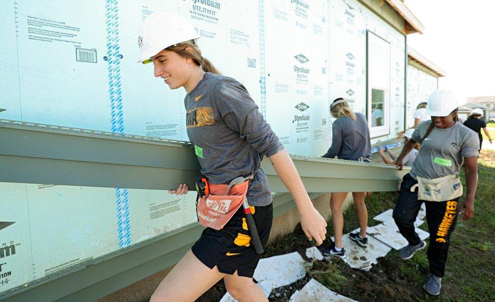 Iowa’s Kate Martin (from left) and Tomi Taiwo carry a piece of siding as they work on a Habitat for Humanity Women Build project in Iowa City on Wednesday, Sep 25, 2019. (Stephen Mally/hawkeyesports.com)