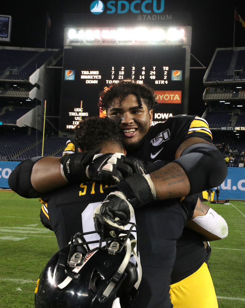 Iowa Hawkeyes offensive lineman Tristan Wirfs (74) hugs defensive back Geno Stone (9) after their win against USC in the Holiday Bowl Friday, December 27, 2019 at San Diego Community Credit Union Stadium. (Brian Ray/hawkeyesports.com)