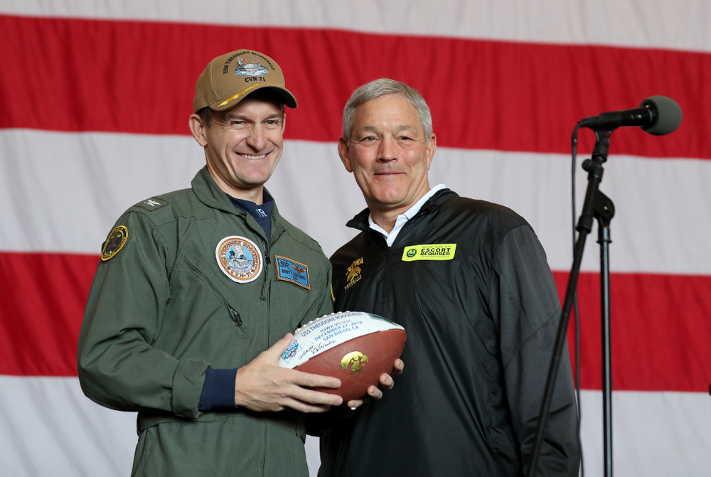 Iowa Hawkeyes head coach Kirk Ferentz presents a ball to Captain Brett Crozier during a tour of the USS Theodore Roosevelt (CVN-71) Tuesday, December 24, 2019 at the Naval Base Coronado. (Brian Ray/hawkeyesports.com)