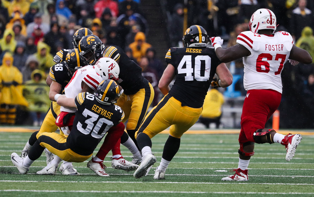 Iowa Hawkeyes defensive back Michael Ojemudia (11), Iowa Hawkeyes linebacker Jack Hockaday (48) and Iowa Hawkeyes defensive back Jake Gervase (30) make a tackle during a game against Nebraska at Kinnick Stadium on November 23, 2018. (Tork Mason/hawkeyesports.com)