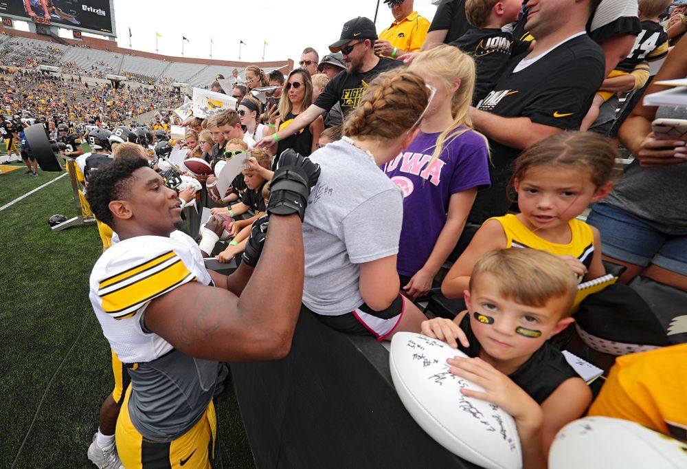 Iowa Hawkeyes defensive end Chauncey Golston (57) signs an autograph on a shirt during Kids Day at Kinnick Stadium in Iowa City on Saturday, Aug 10, 2019. (Stephen Mally/hawkeyesports.com)
