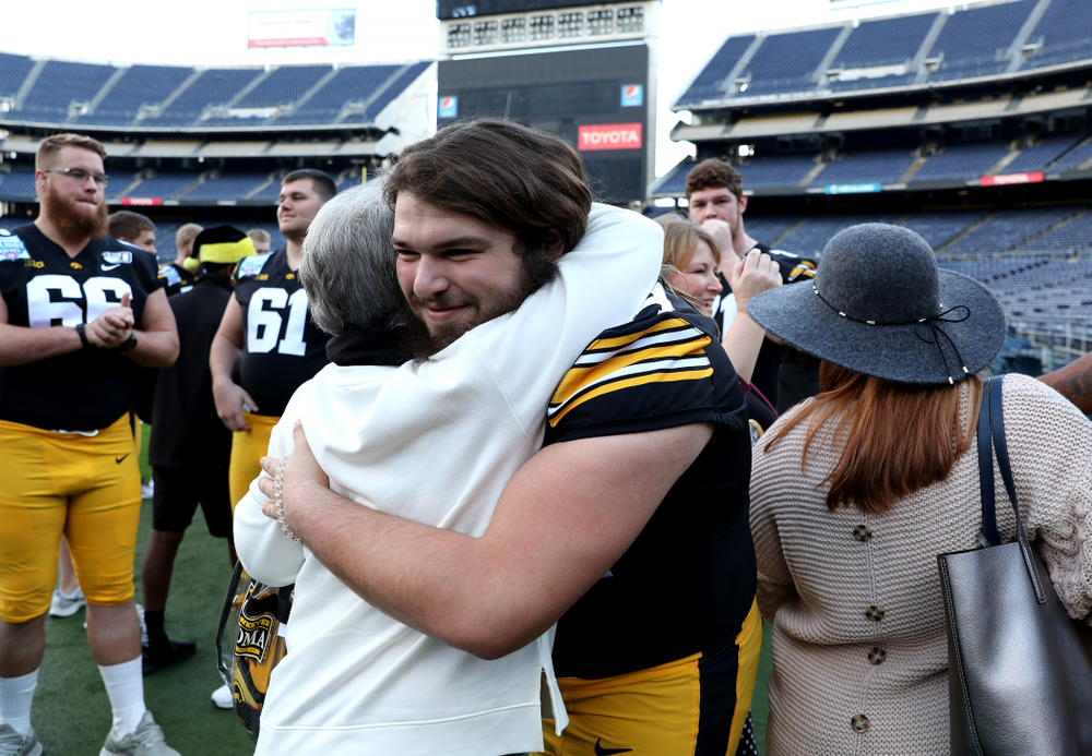 Iowa Hawkeyes offensive lineman Kyler Schott (64) hugs family members following the team photo Wednesday, December 25, 2019 at SDCCU Stadium in San Diego. (Brian Ray/hawkeyesports.com)
