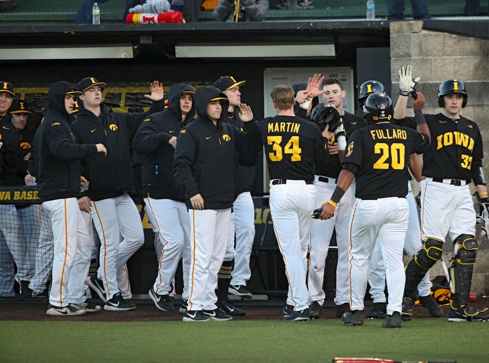 Iowa left fielder Austin Martin (34) and infielder Izaya Fullard (20) are greeted by teammates after scoring during the fifth inning of their game at Duane Banks Field in Iowa City on Tuesday, March 3, 2020. (Stephen Mally/hawkeyesports.com)