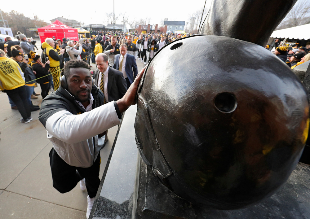 Iowa Hawkeyes linebacker Amani Jones (52) touches the helmet on the Nile Kinnick statue before their game at Kinnick Stadium in Iowa City on Saturday, Nov 23, 2019. (Stephen Mally/hawkeyesports.com)
