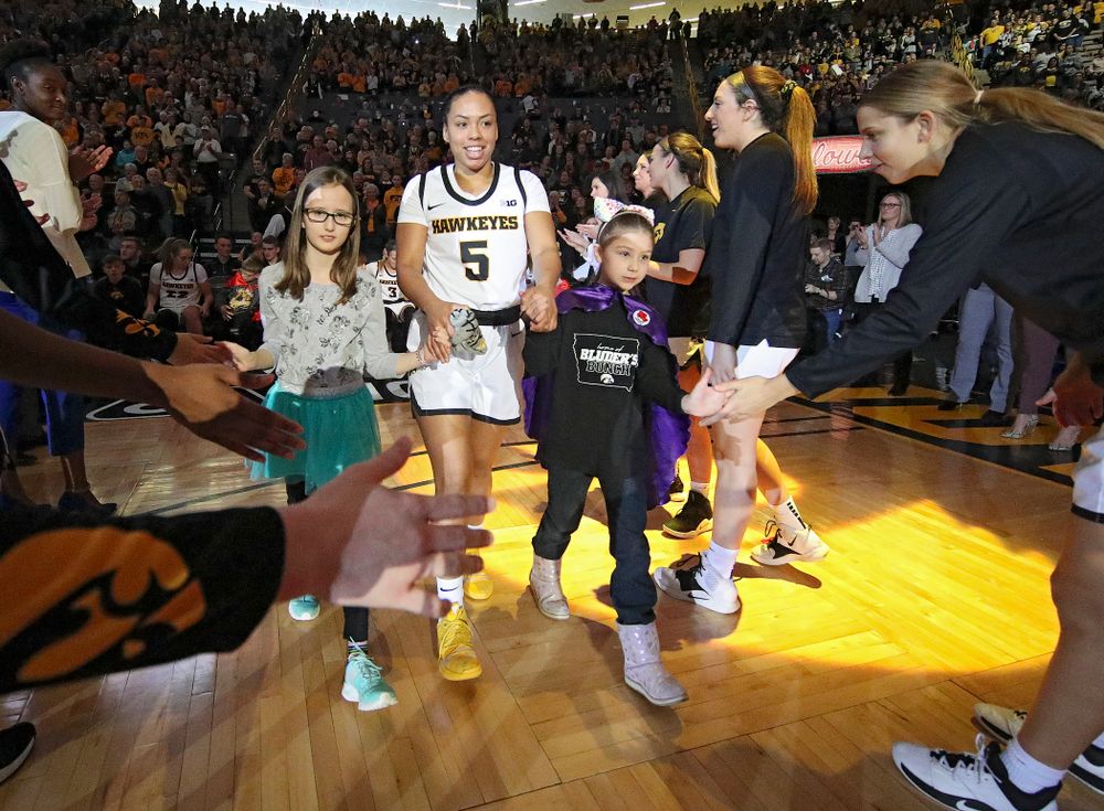 Iowa Hawkeyes guard Alexis Sevillian (5) is introduced with two Go Red for Women Movement Heart Champions before the start of their game at Carver-Hawkeye Arena in Iowa City on Sunday, January 26, 2020. (Stephen Mally/hawkeyesports.com)