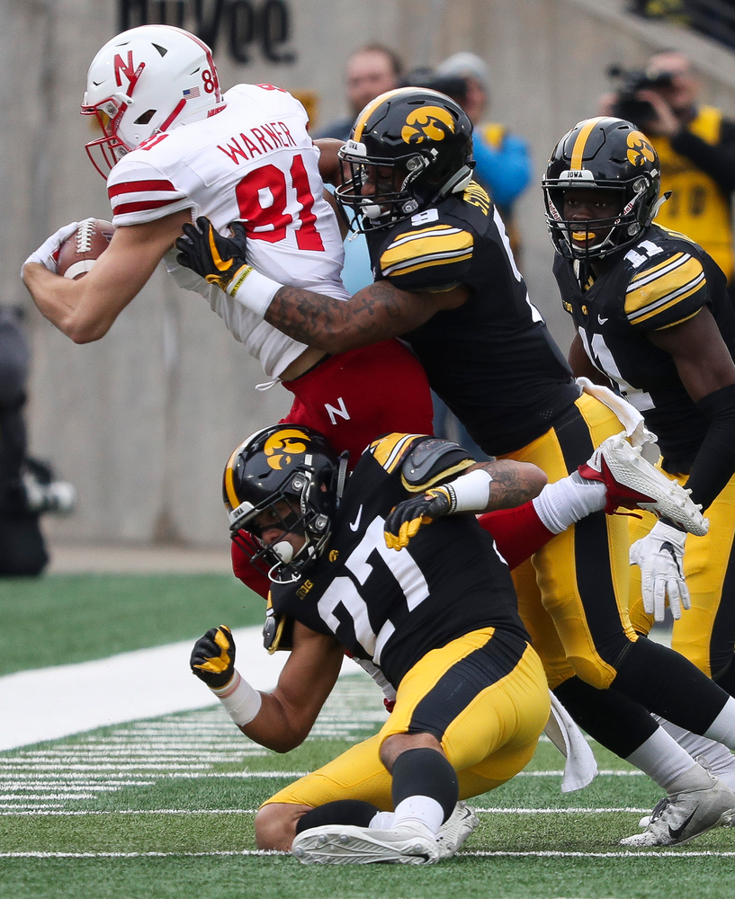 Iowa Hawkeyes defensive back Amani Hooker (27), Iowa Hawkeyes defensive back Geno Stone (9) and Iowa Hawkeyes defensive back Michael Ojemudia (11) make a tackle during a game against Nebraska at Kinnick Stadium on November 23, 2018. (Tork Mason/hawkeyesports.com)