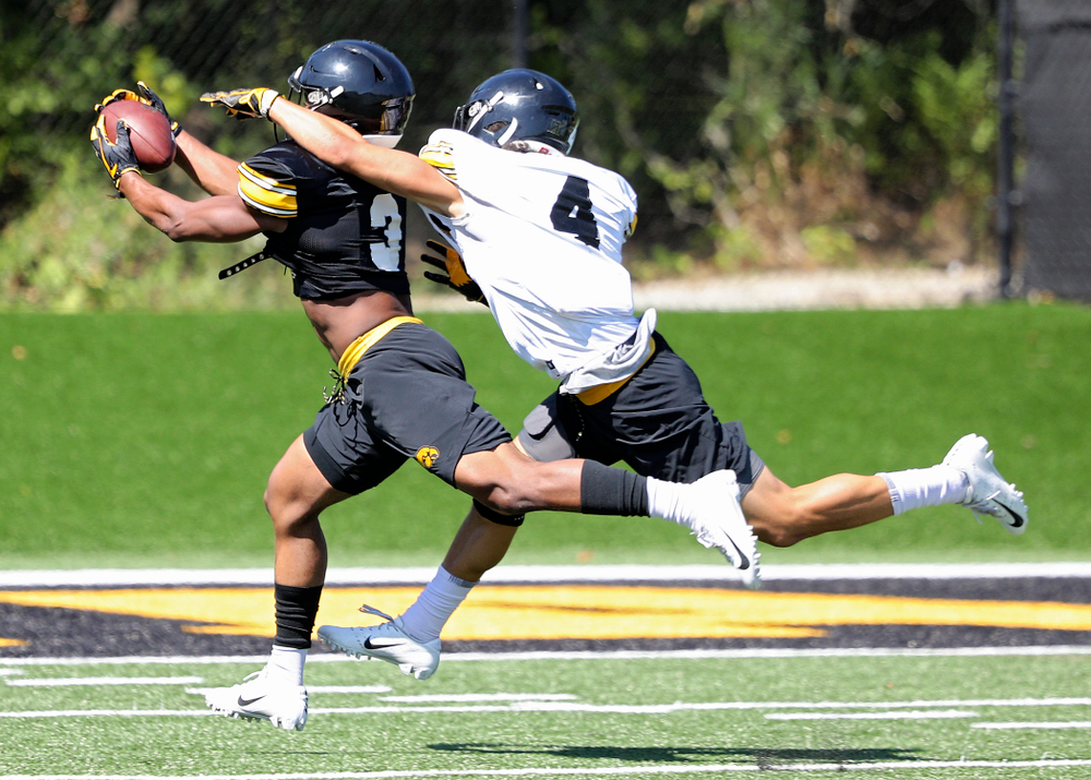Iowa Hawkeyes wide receiver Tyrone Tracy Jr. (3) pulls in a pass around the hand of defensive back Dane Belton (4) during Fall Camp Practice No. 7 at the Hansen Football Performance Center in Iowa City on Friday, Aug 9, 2019. (Stephen Mally/hawkeyesports.com)