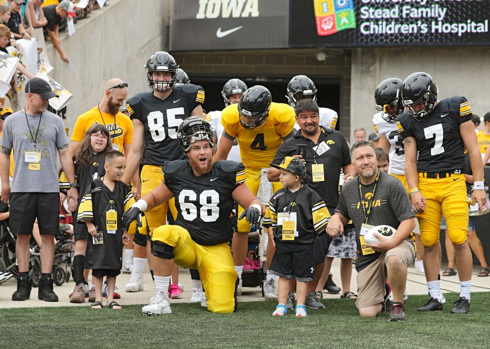 Kid Captains Skylar Hardee (left) and Jeg Weets (right) walk with Iowa Hawkeyes offensive lineman Landan Paulsen (68) prepare to swarm during Kids Day at Kinnick Stadium in Iowa City on Saturday, Aug 10, 2019. (Stephen Mally/hawkeyesports.com)