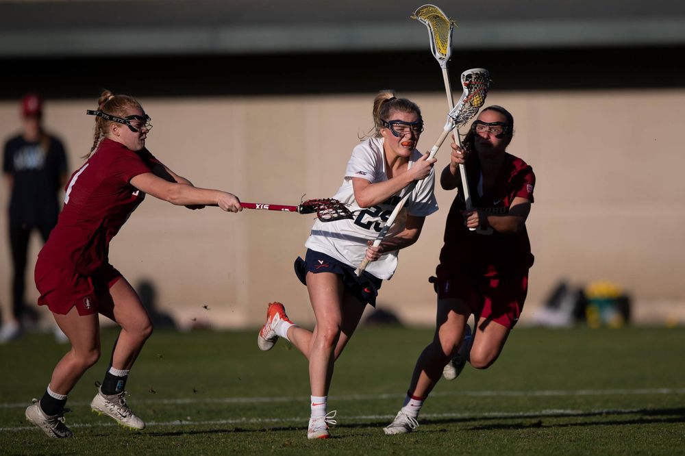STANFORD, California - FEBRUARY 14: Virginia Cavaliers midfield Courtlynne Caskin (25) is defended by Stanford Cardinal defense Maggie Bellaschi (11) and midfield Chelsea Trattner (16) during the second half at Cagan Stadium on February 14, 2020 in Stanford, California. The Virginia Cavaliers defeated the Stanford Cardinal 12-11. (Photo by Jason O. Watson)