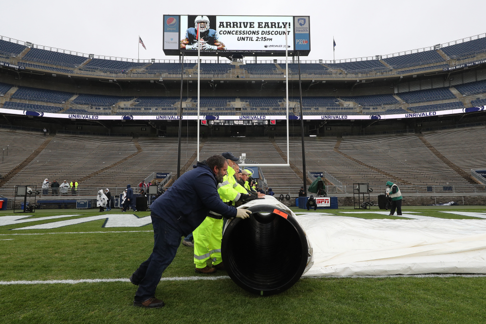 The grounds crew rolls up the tarps before the Iowa Hawkeyes game against the Penn State Nittany Lions Saturday, October 27, 2018 at Beaver Stadium in University Park, Pa. (Brian Ray/hawkeyesports.com)